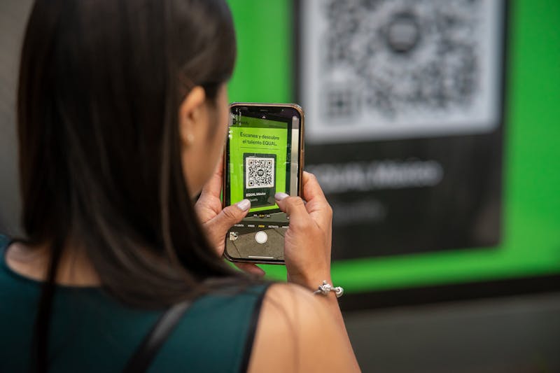Frau scannt einen QR-Code auf einem Plakat mit dem Smartphone